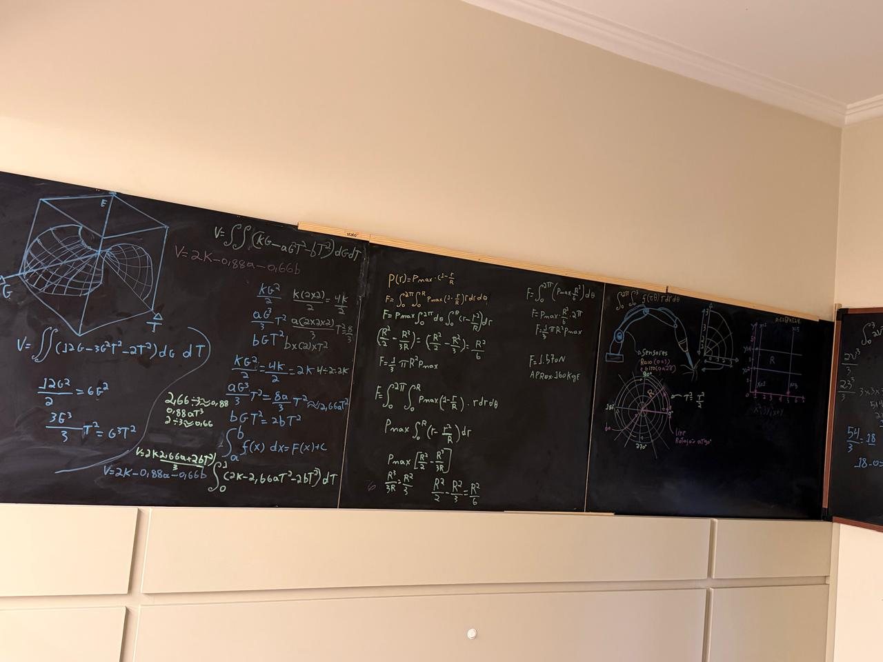 Quadro-negro com integrais duplas, a força de uma pressão em coordenadas polares e um braço com sensores
